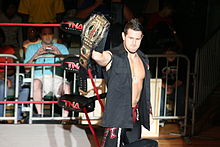 Shelley posing with a TNA World Tag Team Championship belt.