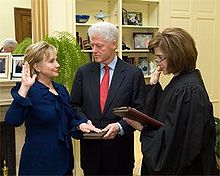 Clinton takes the oath of office as Secretary of State, administered by Associate Judge Kathryn Oberly, as Bill Clinton holds the Bible.