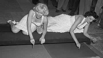 Marilyn Monroe and Russell putting signatures, hand and foot prints in cement at Grauman's Chinese Theatre, 1953