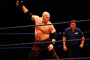 Kane raises his right hand in anticipation of the chokeslam.