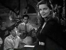 Bacall in her first movie, To Have and Have Not; Hoagy Carmichael is in the background playing the piano