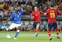 Mario Balotelli shooting at goal and evading Spain defender Sergio Ramos and Sergio Busquets in the final of Euro 2012.