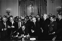 President Johnson signs the Civil Rights Act of 1964. Among the guests behind him is Martin Luther King.