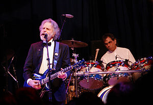 Mickey Hart (in background, playing drums) and Bob Weir (playing guitar) performing at the Mid-Atlantic Inaugural Ball during the presidential inauguration of Barack Obama, January 20, 2009.