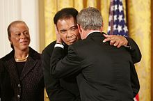 As Mrs. Lonnie Ali looks on, President George W. Bush embraces Muhammad Ali after presenting him with the Presidential Medal of Freedom on November 9, 2005, during ceremonies at the White House.