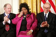 Aretha Franklin wipes a tear after being honored with the Presidential Medal of Freedom on November 9, 2005, at the White House. Seated with her are fellow recipients Robert Conquest, left, and Alan Greenspan
