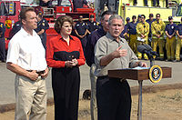 With Schwarzenegger and Senator Dianne Feinstein behind him, President George W. Bush comments on wildfires and firefighting efforts in California, October 2007
