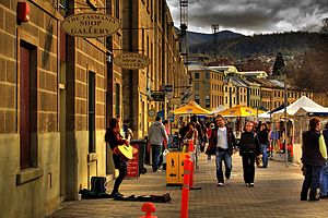 Salamanca Place, Hobart (2007). In mid-1974 Kelly made his first public performance in a folk club along this street, "[It] was a row of warehouses gradually being converted into galleries, shops and cafés. The club was upstairs above a jewellery and craft store. Tables and chairs on a wooden floor with a small stage ... By the time I got onstage I was shaking. I sang Bob Dylan's 'Girl from the North Country', the Nashville Skyline version, and 'The Streets of Forbes', a folk song about the bushranger Ben Hall. Somehow I got through my two-song gig, headed straight for the bar for more beer..." – Kelly (2010), How to Make Gravy, pages 16–18.[29]