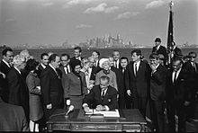President Lyndon B. Johnson signs the Immigration Act of 1965 as Sen. Edward Kennedy, Sen. Robert Kennedy, and others look on.