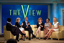 The View's seating arrangement is similar for both the "Hot Topics" segment around a large table and the interview done on the large couches as seen here, with the co-hosts generally sitting in the same order. The View's 2011 panel (left–right Whoopi Goldberg (who replaced O'Donnell as moderator), executive co-producer of the show Barbara Walters, Joy Behar, Sherri Shepherd and Elisabeth Hasselbeck) shown here interviewing US President Barack Obama in July 2010. Because of the seating arrangement O'Donnell was always on the far left and Hasselbeck almost always on the far right.