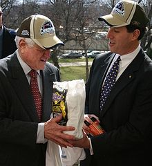 Kennedy (left) and Pennsylvania Senator Rick Santorum after Super Bowl XXXIX in 2005, where Kennedy's Patriots defeated Santorum's Eagles. Here Santorum wears a Patriots hat and presents Kennedy a bag of Philly cheesesteaks.