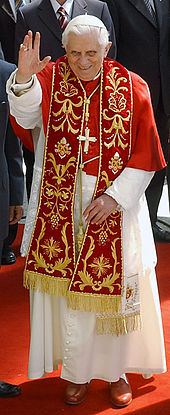 Pope Benedict XVI in choir dress with the red summer papal mozzetta, embroidered red stole, and the red papal shoes.