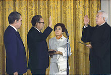 Kissinger being sworn in as Secretary of State by Chief Justice Warren Burger, September 22, 1973. Kissinger's mother, Paula, holds the Bible upon which he was sworn in while President Nixon looks on.