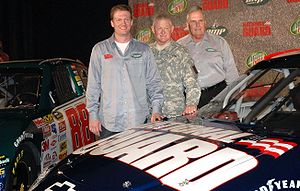 Dale Earnhardt Jr. (left) standing between two different paint schemes for the No. 88 Chevy, with Lt. Gen. Clyde A. Vaughn, director of the Army National Guard, and Rick Hendrick, in Dallas where the announcement was made on September 19, 2007.